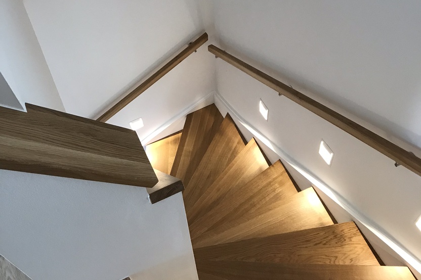 Treppenstufen aus Holz beleuchtet neben weißen Wänden