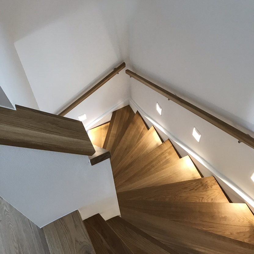 Treppenstufen aus Holz beleuchtet neben wei&szlig;en W&auml;nden