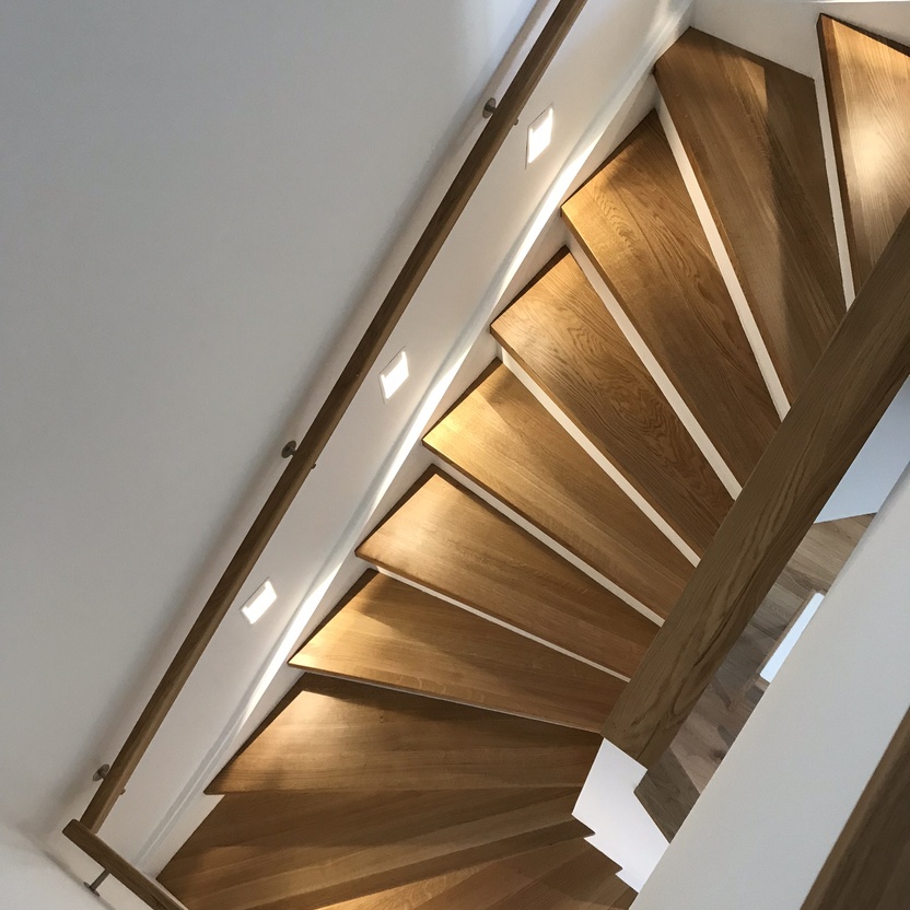 Treppenhaus von oben mit Stufen aus Holz beleuchtet