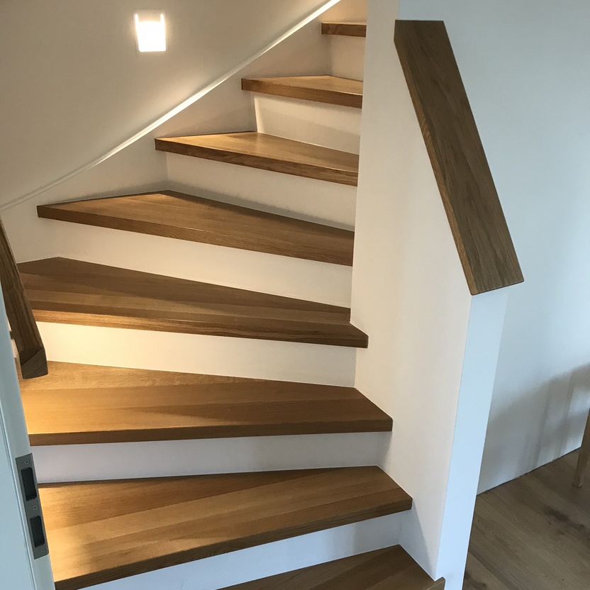 Flur mit Treppenaufgang aus Holz und beleuchteten Stufen