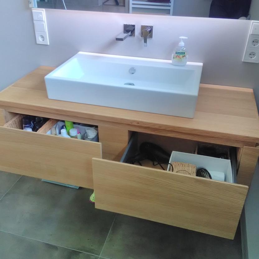 Maßgefertigte Badmöbel aus Holz mit einer modernen rechteckigen Keramikwaschbecken und zwei geöffneten Schubladen, die Badezimmerutensilien zeigen.