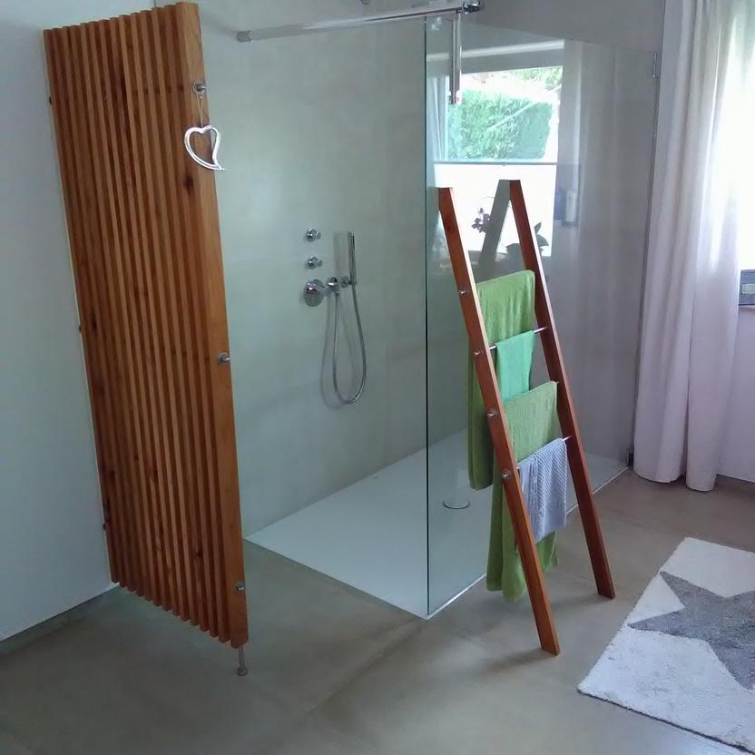 Moderne Dusche mit Glastür, hölzerner Leiter als Handtuchhalter und maßgefertigter Holzklappladen an der Wand.