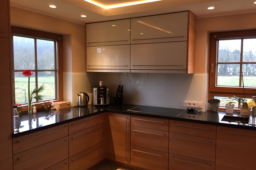 Helle, maßgefertigte Küchenmöbel mit Oberlicht und großem Fenster mit Blick auf eine ländliche Landschaft.