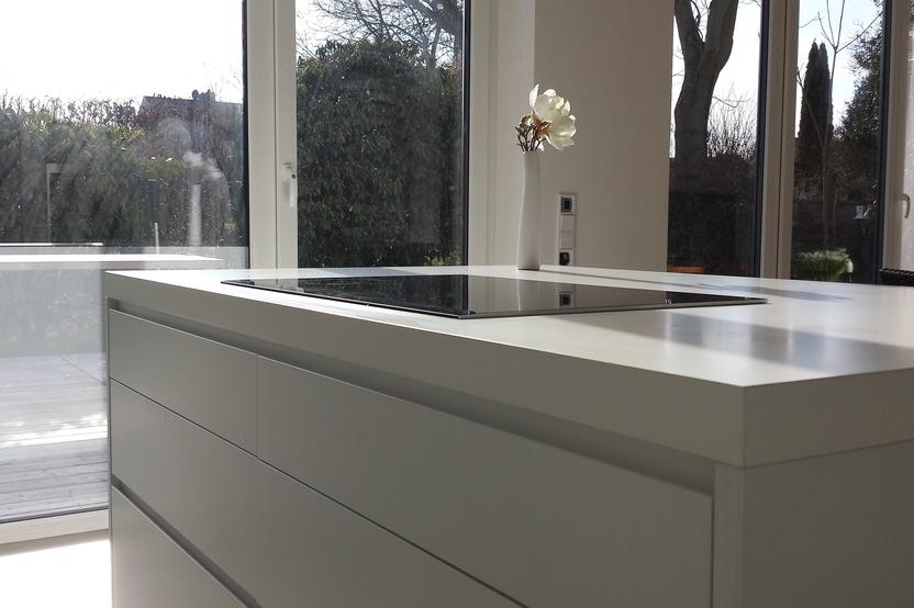 Kochinsel mit weiß matter Lackierung vor Fensterfront