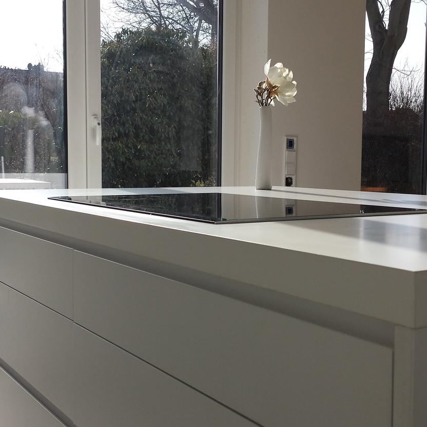 Kochinsel mit weiß matter Lackierung vor Fensterfront