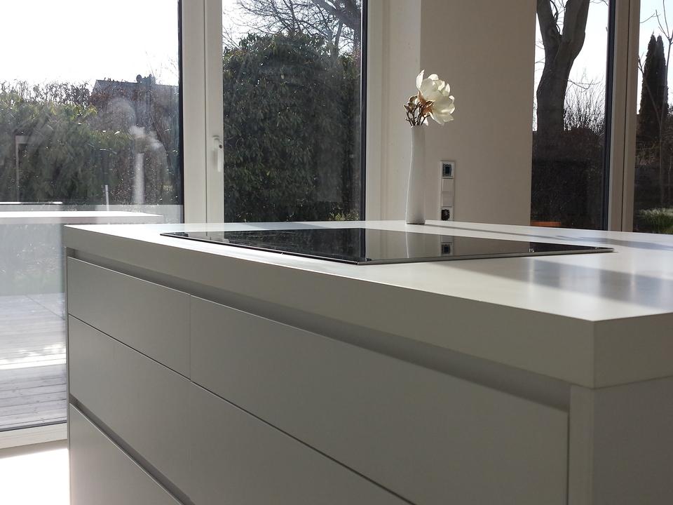 Moderne Einbauküche Kochinsel mit weiß matter Lackierung vor Fensterfront