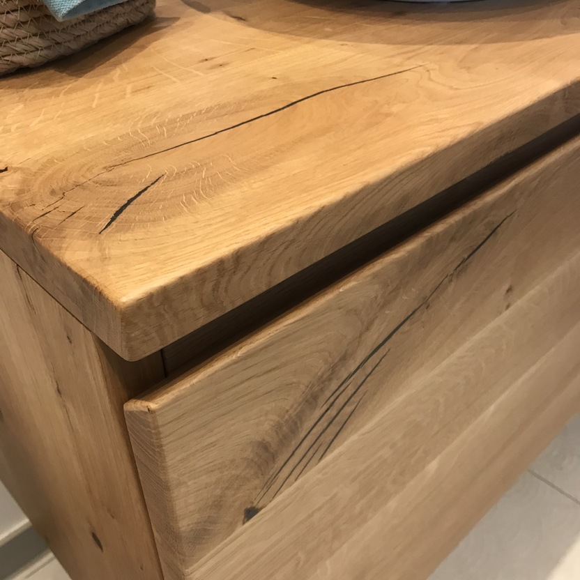 Nahaufnahme eines ma&szlig;gefertigten Badm&ouml;bels aus massivem Holz mit markanter Maserung und Waschtisch