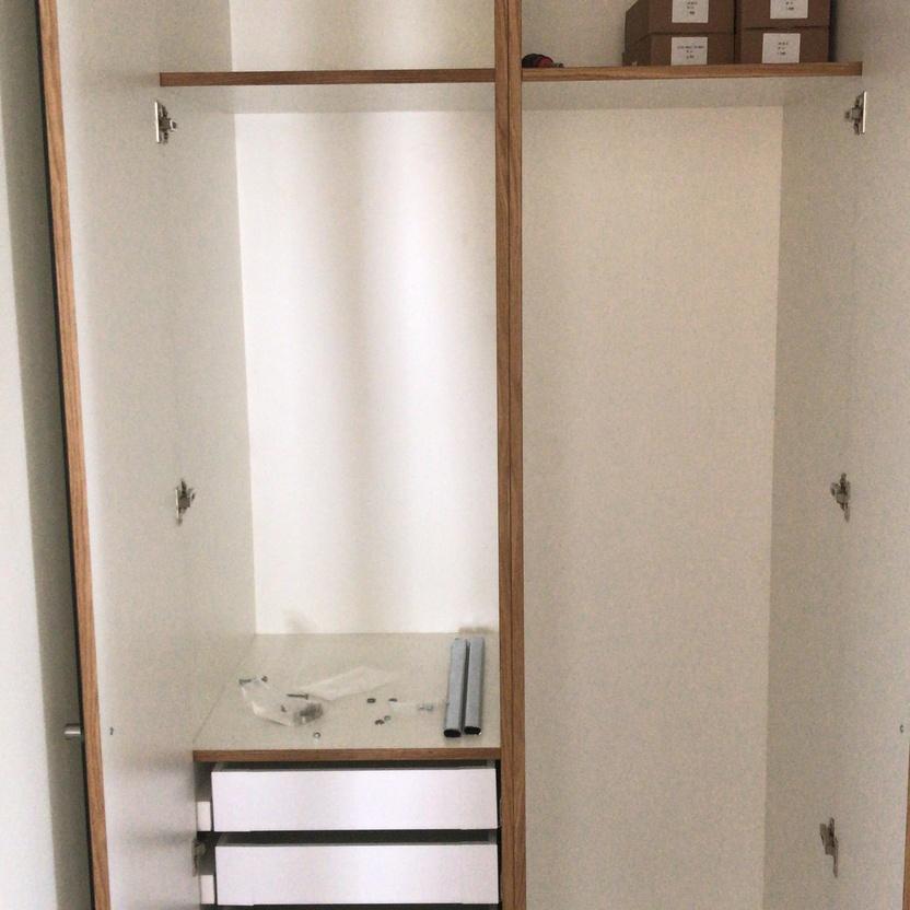 Offener Einbauschrank in einem Badezimmer, teilweise zusammengebaut mit maßgefertigten Badmöbeln, einschließlich Schubladenelementen.