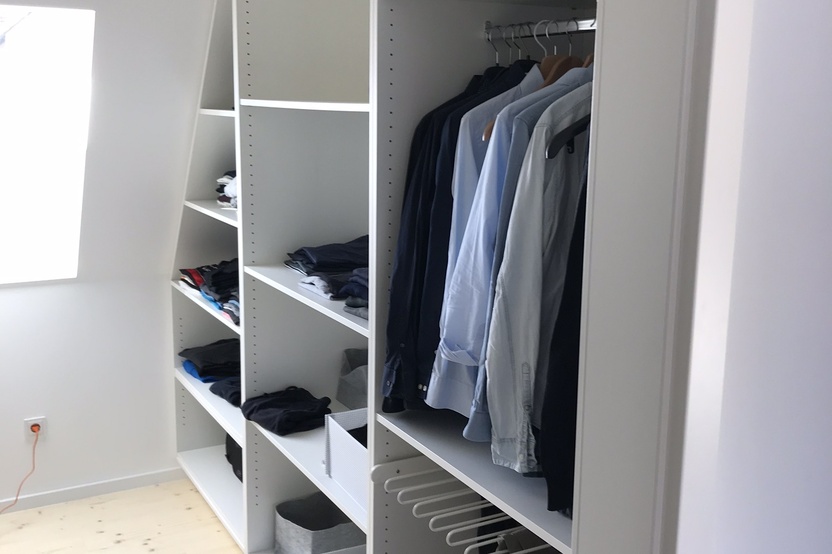 Offener Kleiderschrank unter Dachschräge aus weißem Holz