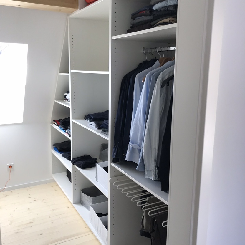 Offener Kleiderschrank unter Dachschräge aus weißem Holz