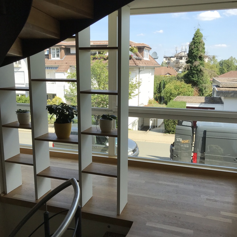 Heller und luftiger Raum mit einem stilvollen weißen Raumteiler, der offene Regalfächer beinhaltet, ideal zur dekorativen und funktionalen Raumaufteilung.