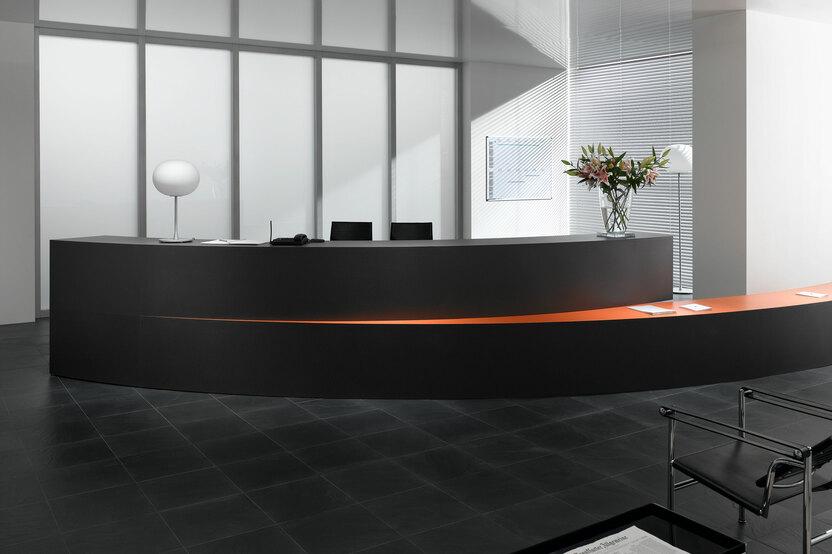 Hotelrezeption mit schwarz lackierter Empfangstheke und orangenem Kontrast