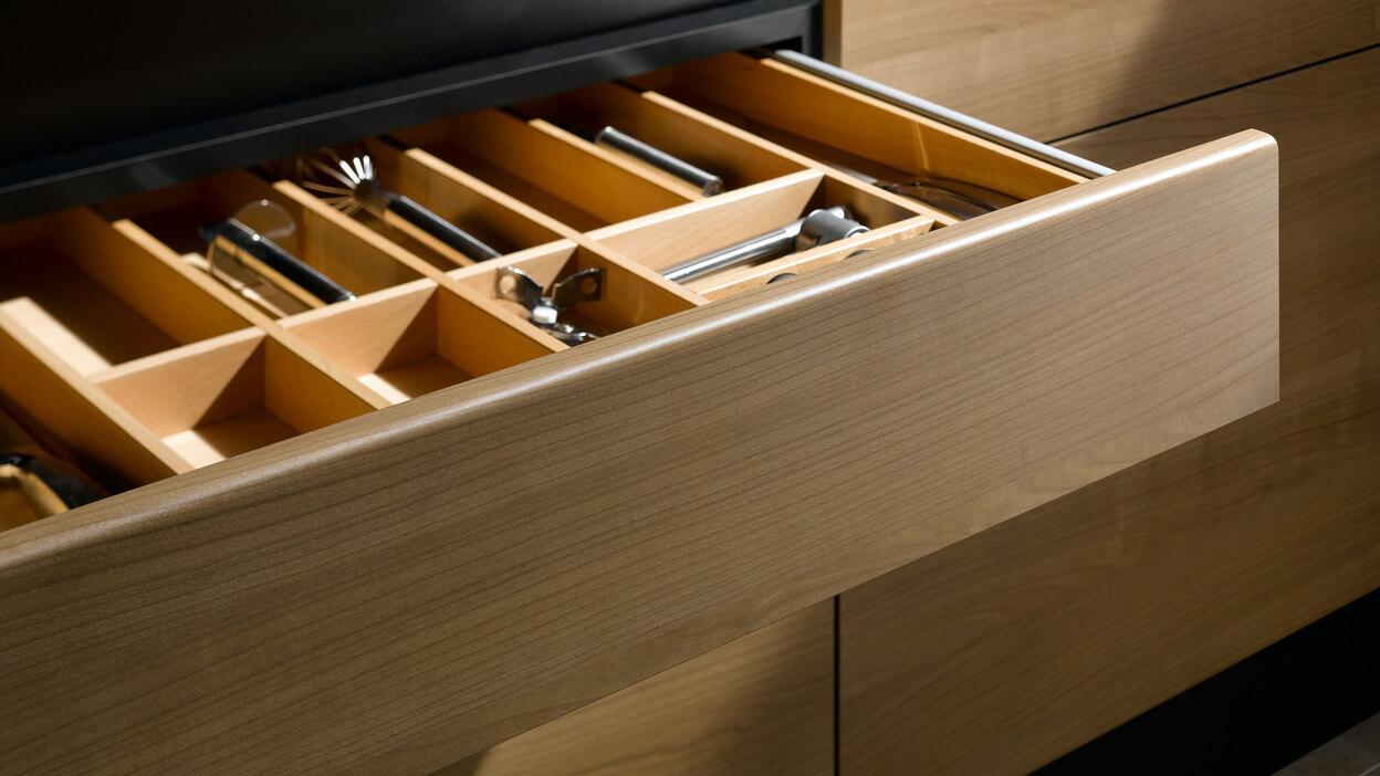 Detailaufnahme einer Besteckschublade aus Massivholz Detailaufnahme einer Besteckschublade aus hellem Massivholz