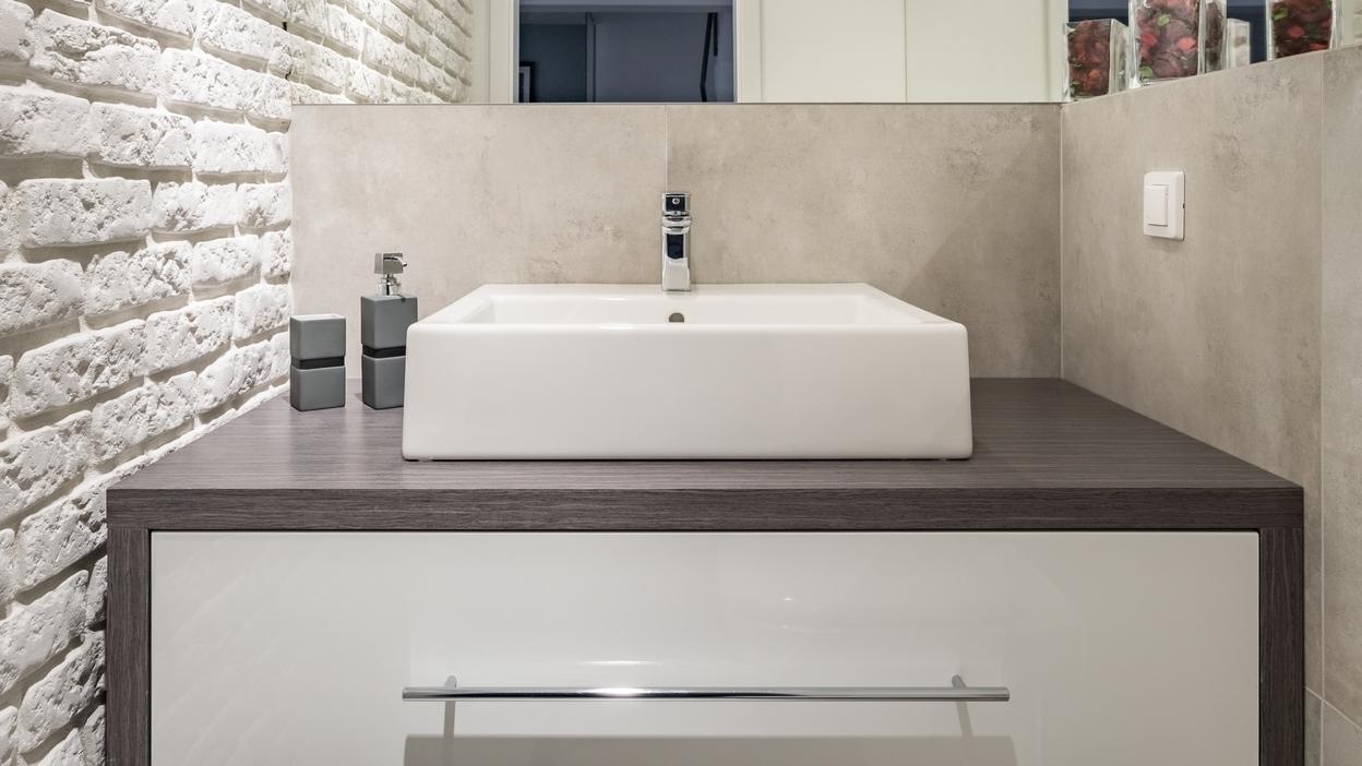 Nischenlösung für Waschtisch im Gäste-WC mit weißer Schublade an Betonwand